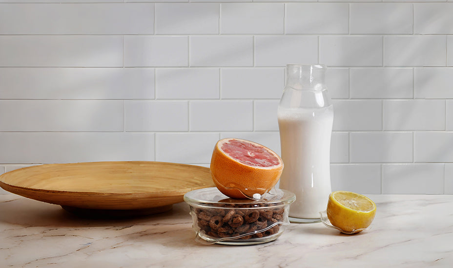 DeliOne Flex'n Fresh Stretch Lid stretched over a glass bottle and half lemon